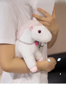 Close-up of white plush pony with pink mane and a small bell held by a model