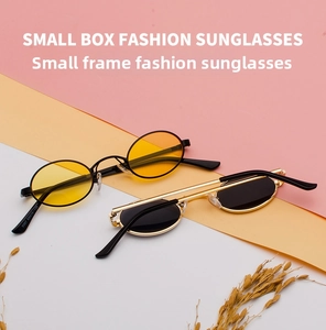 Close-up of small oval retro sunglasses with metal frames in black and gold finishes