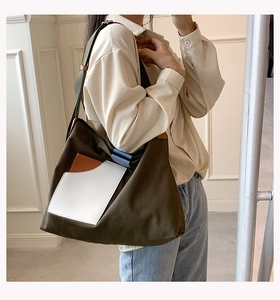 Detail of army green canvas tote bag with contrast pocket shown on model during commute