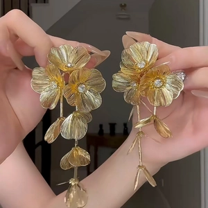 Close-up of golden flower earrings featuring sparkling rhinestones and petal details