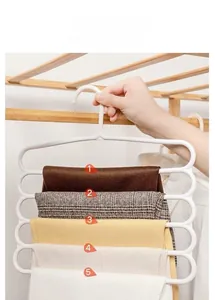 Space-saving 5-layer pants hanger with five tiers holding different trousers in a closet