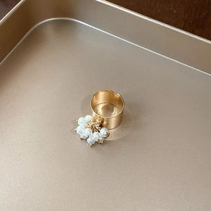 Detailed macro shot of a gold open ring featuring a lush cluster of white pearls