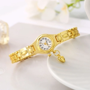 Detail view of gold quartz watch with heart pendant and white dial on a tray