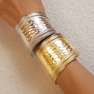 Detailed macro view of hammered texture on wide metallic gold and silver open bangles