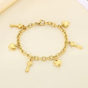 Detail view of gold stainless steel bracelet with heart and key charms on leather base