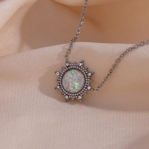 Close-up of silver sun pendant necklace with opal center and rhinestones on beige fabric