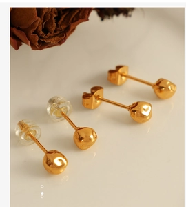 Detailed view of minimalist gold bean earrings with irregular hammered texture and backings