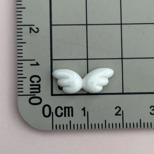 Nahaufnahme eines weißen Harzflügels auf einem Lineal zur Anzeige der 1,5 cm Breite