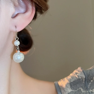 Detailed close-up of French vintage double teardrop pearl earrings on model