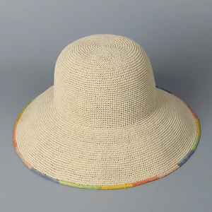 Close-up of hand-woven straw sun hat showing detailed beige texture and colorful stitched edge