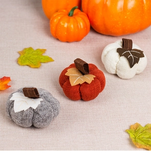 Detailed close-up of knitted orange, grey and white pumpkins for harvest festival decor