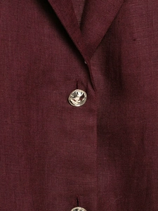 Detailed macro view of burgundy linen fabric texture and unique silver metal button