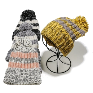 Thick knit beanies with faux fur pom-poms in striped patterns for winter warmth