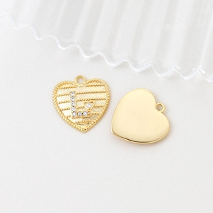 Macro detail of heart-shaped 14k gold plated pendant with cubic zirconia letter L