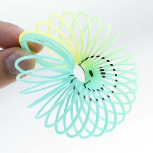 Close-up of flexible yellow and green gradient plastic spring toy with a black smiley face