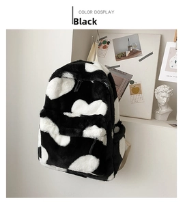 Close-up of soft plush backpack with black and white heart pattern and metal zippers