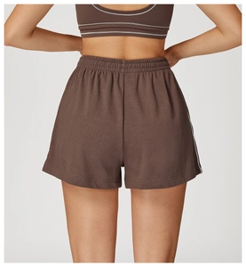 Dettaglio della vita alta elastica su pantaloncini sportivi marroni con piping bianco laterale