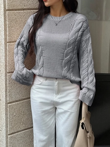 Detail of grey cable-knit sweater texture with long sleeves on a model in sunlight
