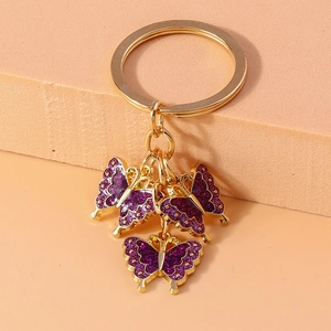 Detail of three purple glitter enamel butterfly charms on a gold metal keychain ring