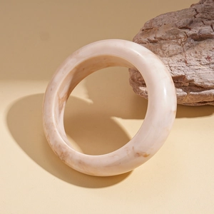 Détail macro d'un large bracelet en résine avec motif marbré beige et finition polie