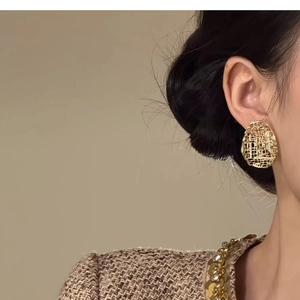 Detail of large gold-plated oval mesh earrings on model for a vintage luxury aesthetic