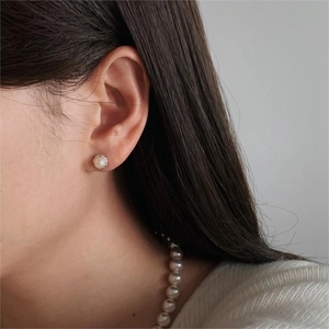 Close-up of classic round pearl stud earring worn by model with matching necklace