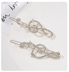 Detailed macro view of silver music note and butterfly hair clips with sparkling rhinestones