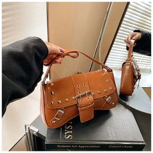 Detailed close-up of a brown punk shoulder bag with silver studs and eyelet straps