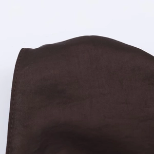 Detailed close-up of dark brown satin fabric texture with refined stitching edges