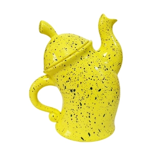 Detail of yellow ceramic tea pot with black spotted glaze and polished glossy finish