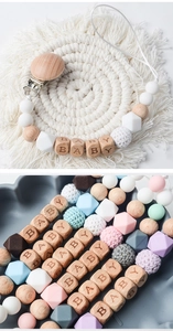 Close-up of beech wood and silicone baby pacifier clips featuring wooden BABY letter beads