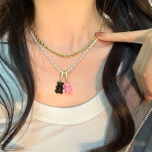 Dettaglio di collana a doppio strato in oro e perle con ciondoli a forma di orso