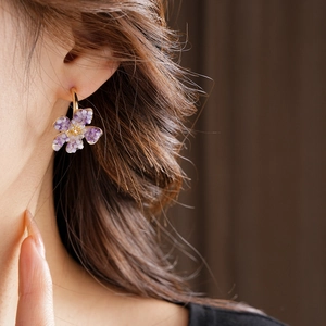 Close-up of vintage C-shape flower earrings with purple gradient beads on a model