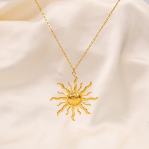 Macro shot of 18k gold plated sunburst pendant on minimalist textured fabric background