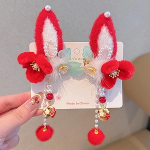 Detail of red and white rabbit ear hair clips with tassels and floral accents for girls