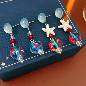 Detailed view of nautical star and blue glass bead earrings on a navy gift box