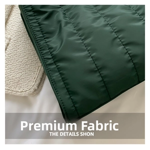 Detail of green quilted puffer tote bag fabric featuring smooth satin finish and padding