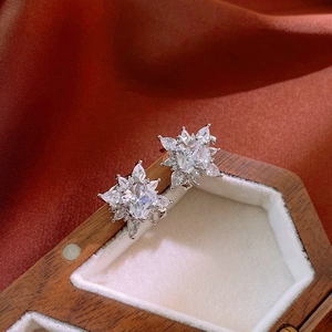 Detailed view of silver snowflake zircon clip-on earrings on white velvet jewelry box