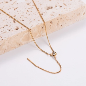 Macro view of minimalist golden stainless steel ear threader with bead and chain detail