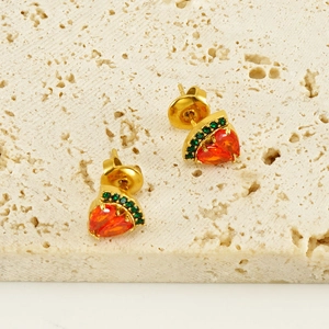Minimalistische vergoldete Erdbeere-Ohrstecker mit roten Zirkonia auf einem Natursteinboden