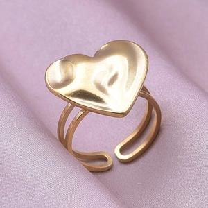 Close-up of golden adjustable heart ring with irregular hammered texture on purple silk