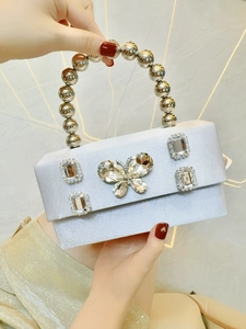 Close-up of sparkling rhinestone butterfly and beaded handle on silver satin bag