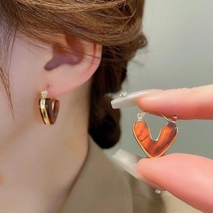 Gros plan sur les boucles d'oreilles cœur en résine ambre avec bordure dorée chic