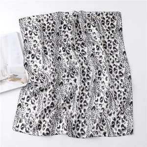 Detailed view of leopard print satin square scarf with soft silky texture on a magazine