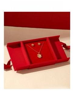 Detailed close-up of a gold floral jewelry set in a luxury red double-door display gift box