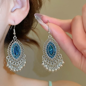 Dettaglio di orecchini vintage in argento con gemma blu ovale e nappine con perline