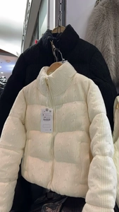 Detail of white cable knit puffer jacket featuring premium golden zipper and soft fabric