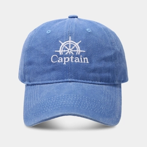 Close-up of white Captain embroidery and wheel logo on blue washed cotton baseball cap