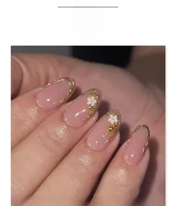 Gros plan d'ongles amande avec fleurs blanches 3D et lignes dorées en relief