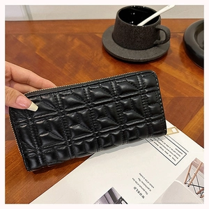 Macro detail of black quilted leather long wallet with golden zipper held by hand